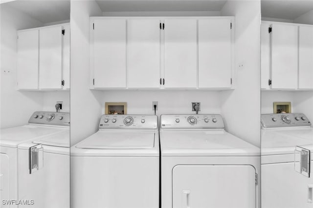 clothes washing area featuring cabinets and separate washer and dryer