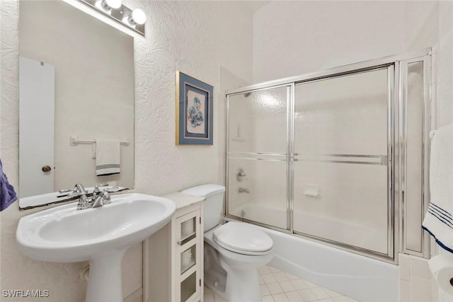 bathroom featuring shower / bath combination with glass door, tile patterned floors, and toilet