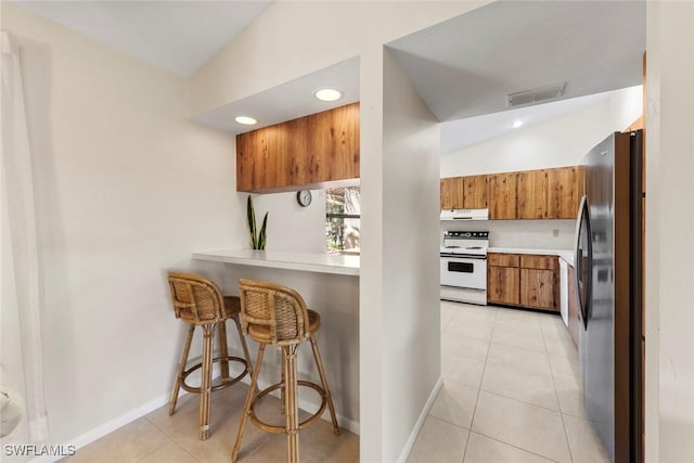 kitchen with stainless steel fridge, white range with electric stovetop, exhaust hood, light tile patterned floors, and lofted ceiling