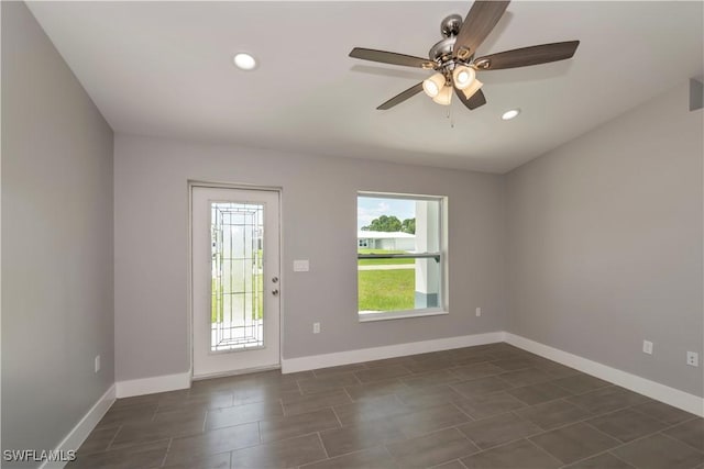 spare room featuring ceiling fan and dark tile patterned floors