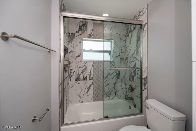 bathroom with toilet and bath / shower combo with glass door