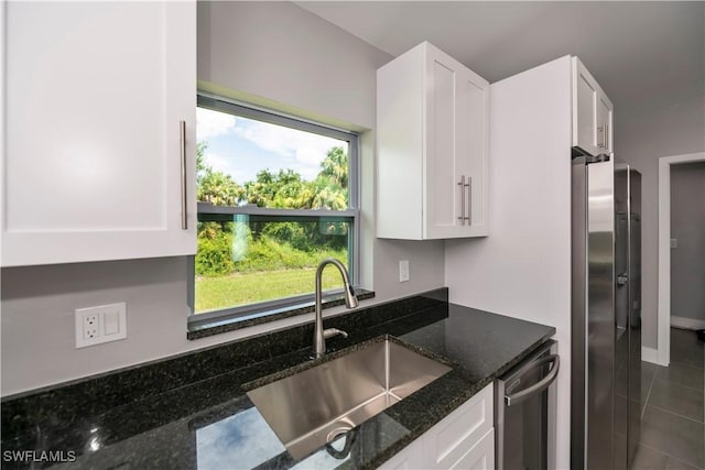 kitchen featuring dark stone counters, dark tile patterned flooring, sink, white cabinetry, and stainless steel appliances