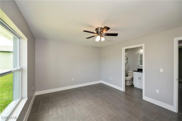 unfurnished bedroom featuring ceiling fan, dark hardwood / wood-style flooring, multiple windows, and ensuite bath