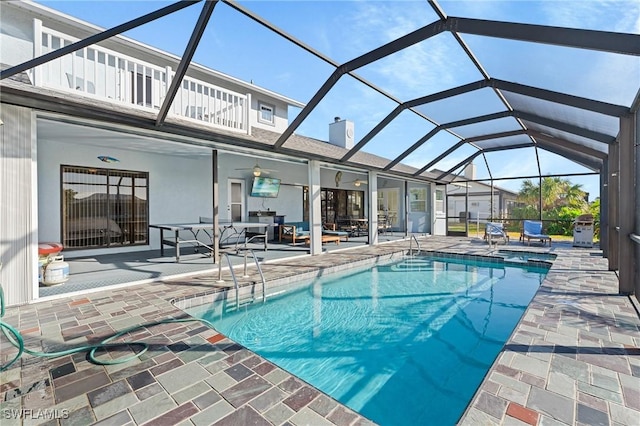 view of pool featuring glass enclosure, ceiling fan, and a patio area