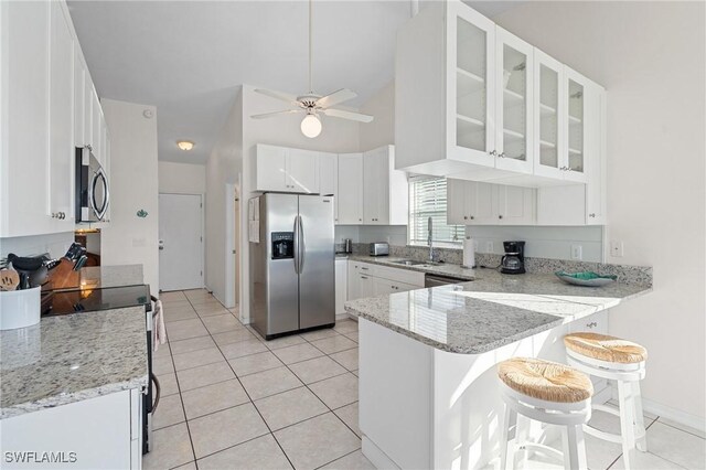 kitchen with sink, stainless steel appliances, kitchen peninsula, a breakfast bar area, and white cabinets