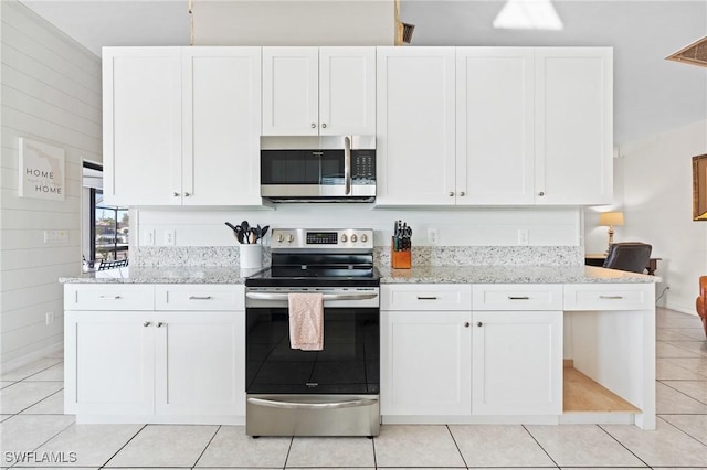 kitchen featuring white cabinets, light tile patterned floors, light stone countertops, and appliances with stainless steel finishes