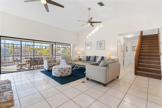 tiled living room with a water view, ceiling fan, and high vaulted ceiling