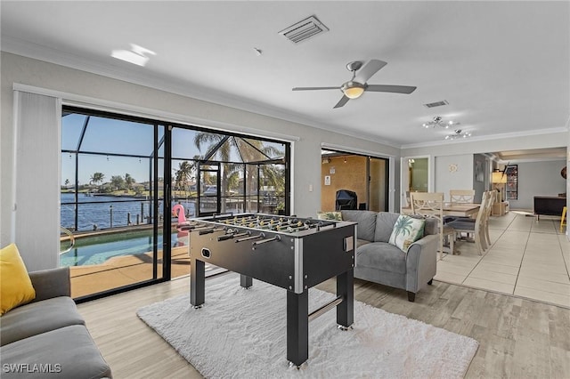 rec room featuring ceiling fan, crown molding, a water view, and light wood-type flooring