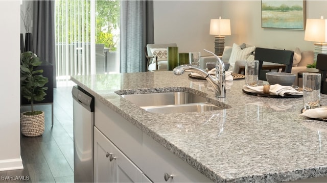 kitchen featuring light stone countertops, white cabinets, dark wood-type flooring, sink, and dishwasher