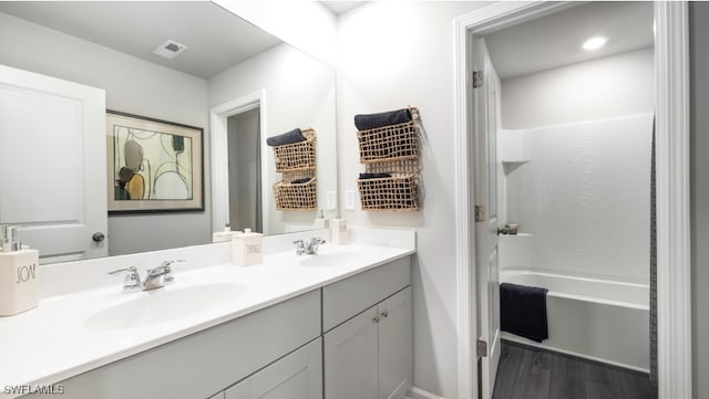 bathroom with wood-type flooring, vanity, and shower / tub combination