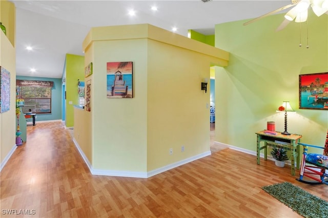 hallway with light wood-type flooring and high vaulted ceiling