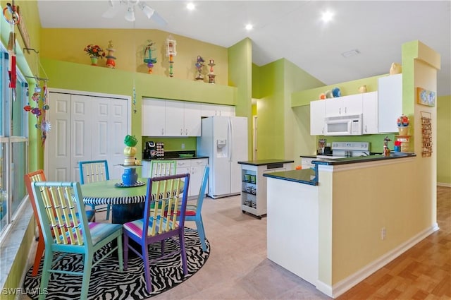 kitchen with white appliances, white cabinets, vaulted ceiling, ceiling fan, and kitchen peninsula