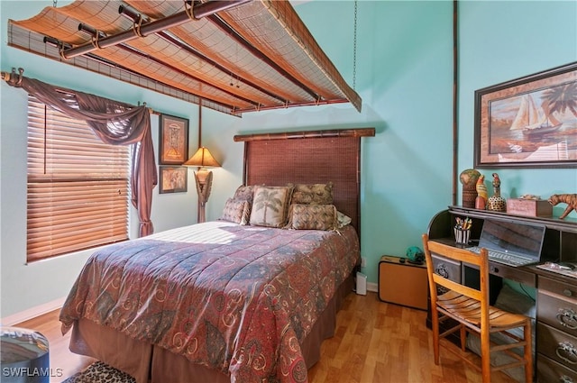 bedroom with beamed ceiling and light hardwood / wood-style flooring