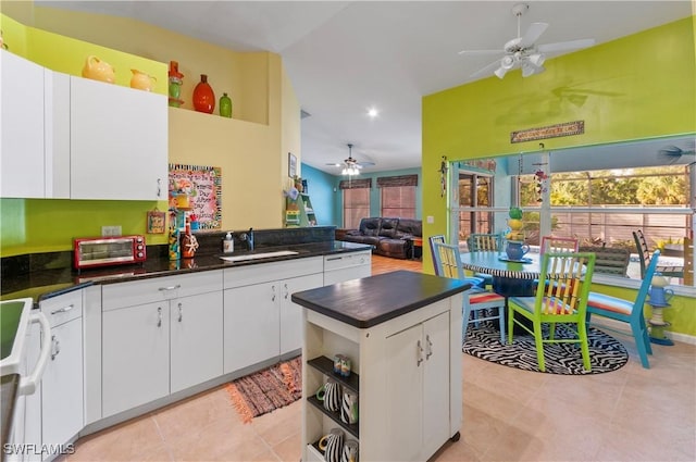 kitchen with stove, white cabinetry, sink, and light tile patterned floors