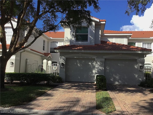 2185 Arielle Dr Unit 1404, Naples, FL 34109 - mediterranean / spanish-style home with stucco siding, a tiled roof, a garage, and decorative driveway