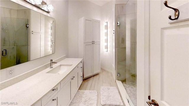 full bathroom featuring a stall shower, wood finished floors, and vanity