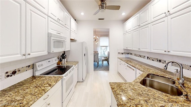 kitchen with white appliances, white cabinets, and a sink