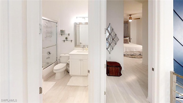 bathroom with bath / shower combo with glass door, vanity, toilet, and wood finished floors