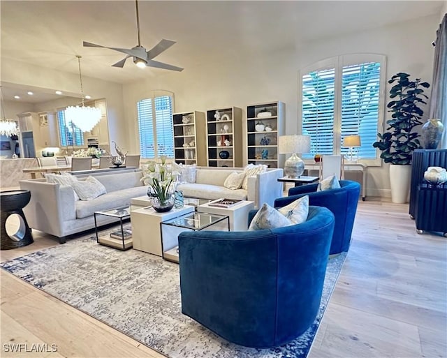 living room featuring ceiling fan with notable chandelier and hardwood / wood-style floors