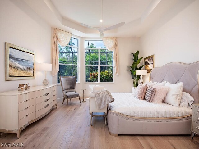 bedroom featuring a tray ceiling and light hardwood / wood-style flooring