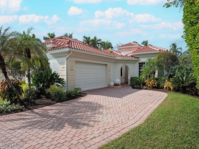 mediterranean / spanish home featuring a garage and a front lawn