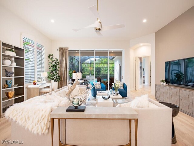 living room featuring ceiling fan, light hardwood / wood-style floors, and a wealth of natural light