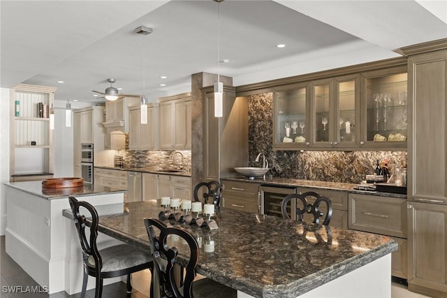 kitchen featuring decorative light fixtures, sink, a large island with sink, and beverage cooler