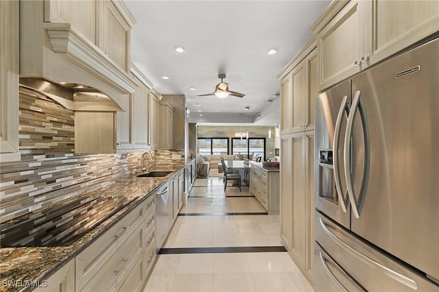 kitchen featuring decorative backsplash, appliances with stainless steel finishes, ceiling fan, sink, and dark stone countertops