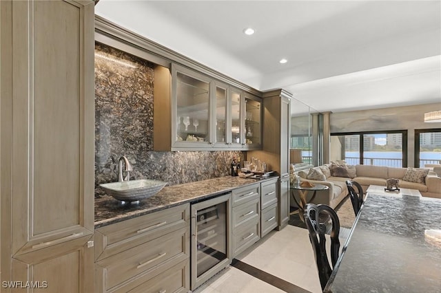 bar featuring tasteful backsplash, sink, dark stone counters, and beverage cooler