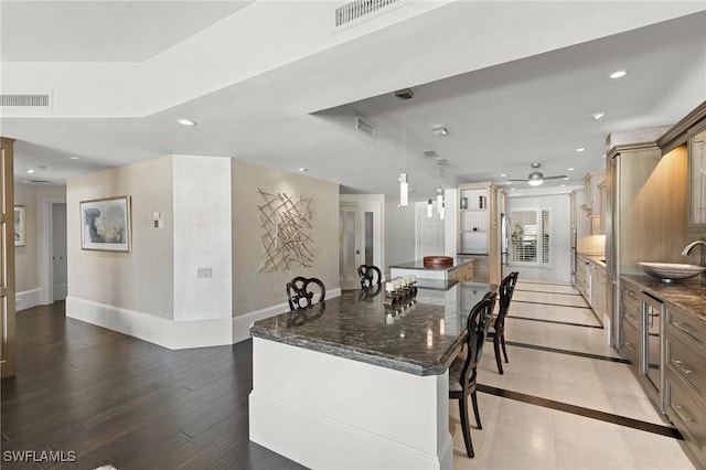 kitchen featuring pendant lighting, light hardwood / wood-style flooring, a kitchen island, and dark stone countertops