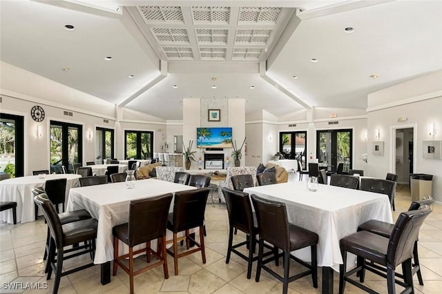 dining room featuring a fireplace, french doors, and vaulted ceiling