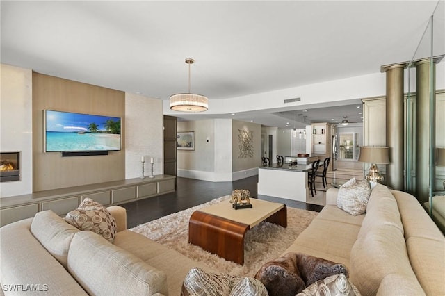 living room with a large fireplace and dark wood-type flooring