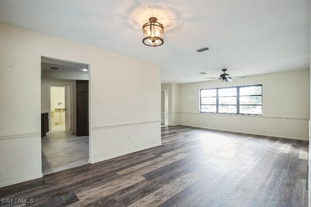 spare room featuring dark hardwood / wood-style flooring and ceiling fan with notable chandelier