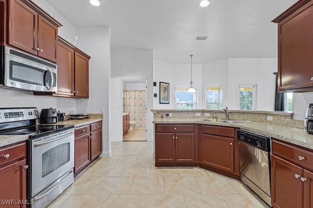 kitchen with hanging light fixtures, light stone counters, sink, and appliances with stainless steel finishes