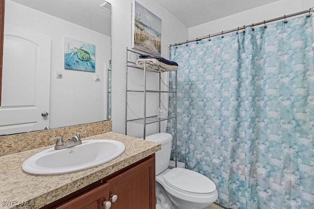 bathroom with vanity, toilet, and a textured ceiling