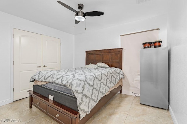 bedroom with light tile patterned flooring, stainless steel refrigerator, a closet, and ceiling fan