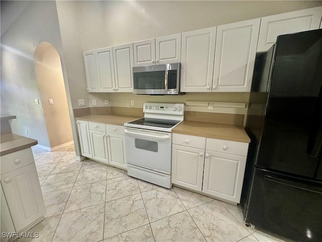 kitchen with white cabinets, black refrigerator, and white electric stove