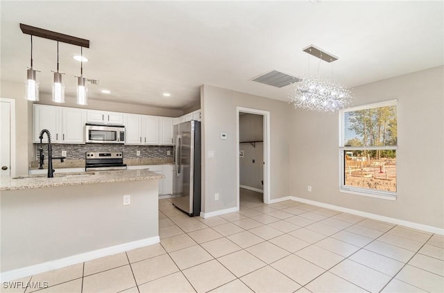 kitchen with pendant lighting, decorative backsplash, light stone counters, white cabinetry, and stainless steel appliances