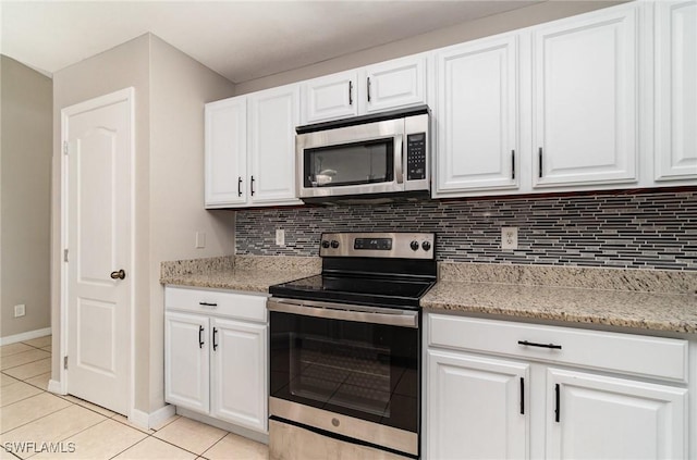 kitchen featuring decorative backsplash, white cabinetry, stainless steel appliances, and light tile patterned floors