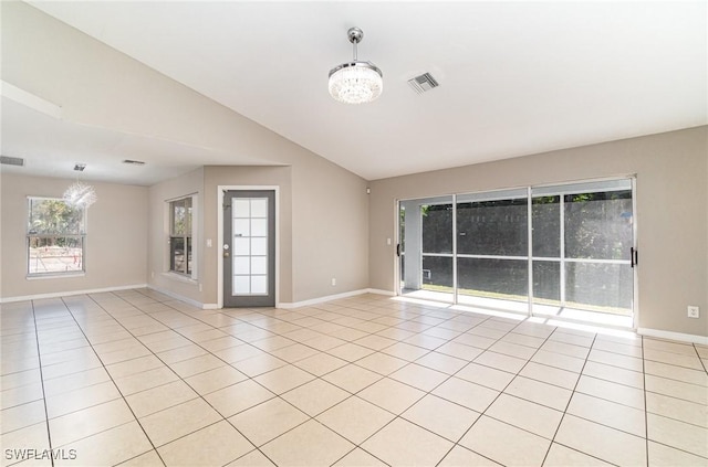 tiled empty room featuring plenty of natural light, lofted ceiling, and an inviting chandelier