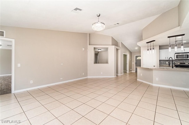 unfurnished living room with a chandelier, light tile patterned floors, sink, and vaulted ceiling