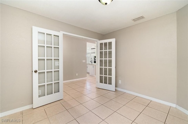 unfurnished room with french doors, light tile patterned flooring, and sink