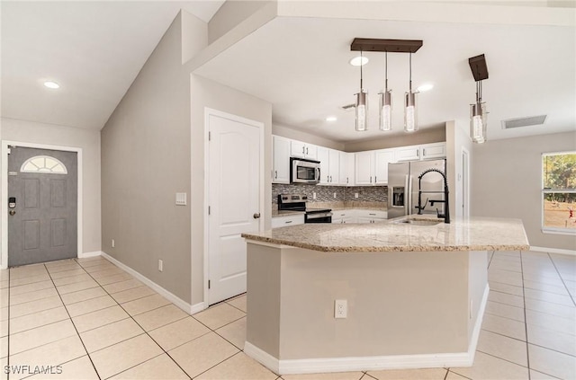 kitchen featuring light stone countertops, stainless steel appliances, pendant lighting, a center island with sink, and white cabinetry