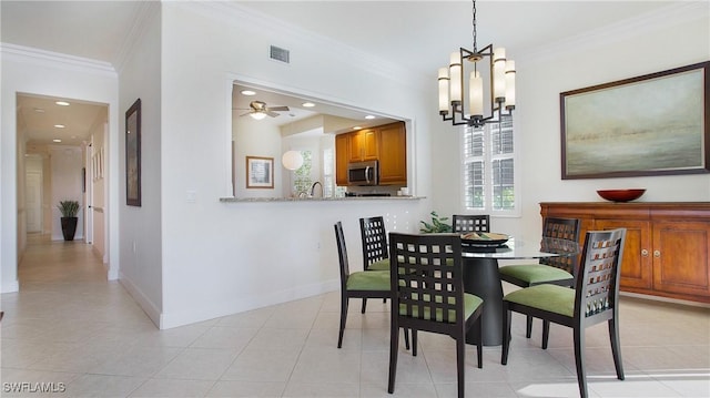 dining space with ceiling fan with notable chandelier, a wealth of natural light, crown molding, and light tile patterned flooring