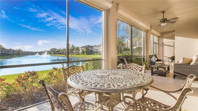 sunroom featuring ceiling fan and a water view