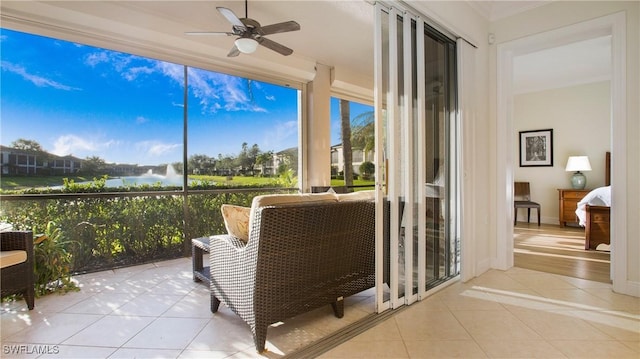 sunroom featuring ceiling fan and a water view