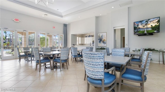 dining space featuring a chandelier, a towering ceiling, and light tile patterned flooring