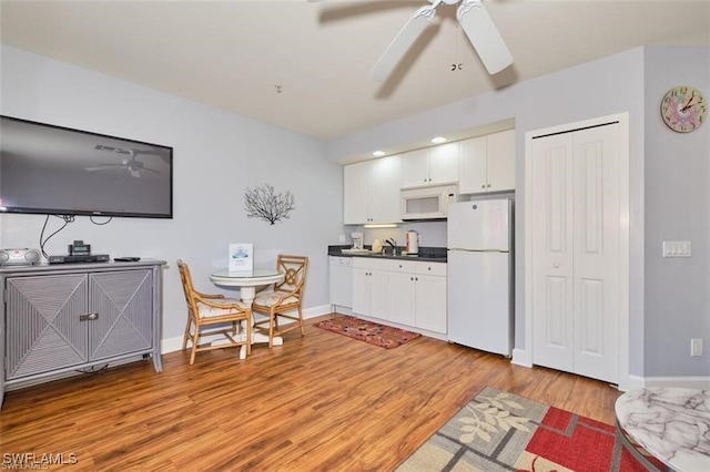 kitchen featuring white cabinets, ceiling fan, white appliances, and light hardwood / wood-style flooring