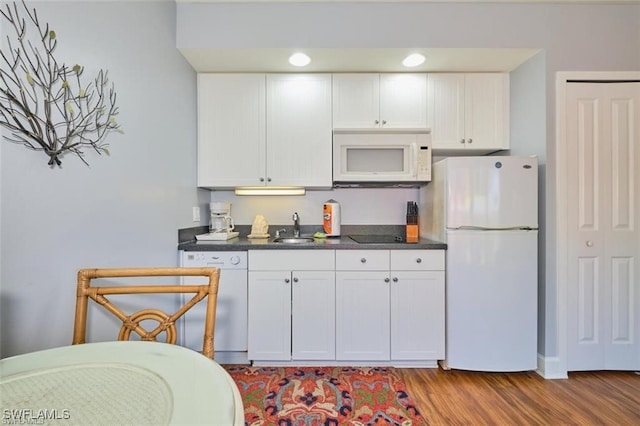 kitchen featuring wood-type flooring, white appliances, white cabinetry, and sink