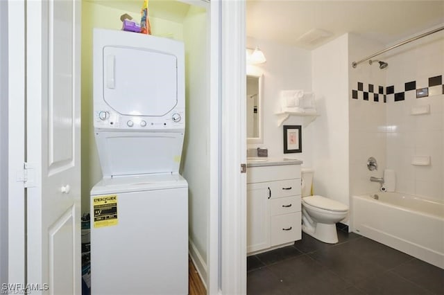 laundry room featuring dark tile patterned flooring and stacked washer / dryer